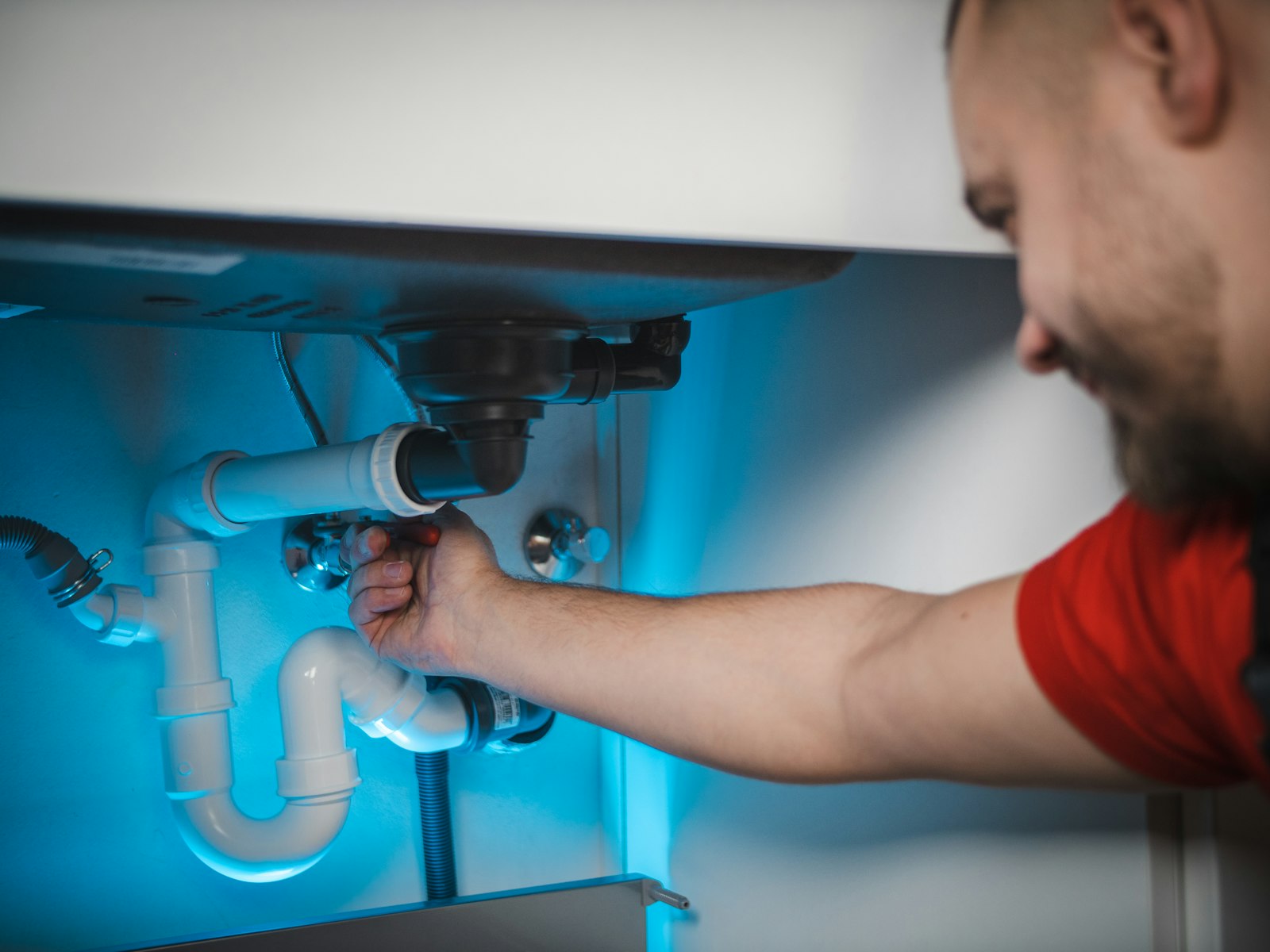 Plumber fitting pipework under a sink